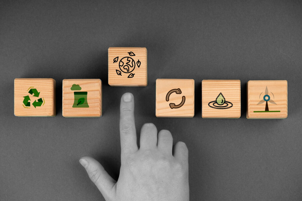 Eine Hand zeigt auf einen Bastein mit einem Icon drauf der die Erde und Recycling symbolisiert